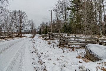 Snow covered road with a split rail fence in a winter setting