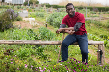 African american man horticulturist with mattock in garden outdoor