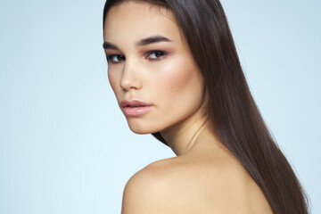 Fototapeta premium Pretty brunette with bared shoulders long hair body care blue background