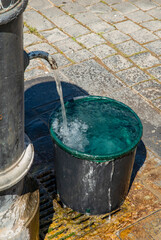 Italy, Rome. Drinking fountain on sidewalk called 'Nasone', water filling bucket.