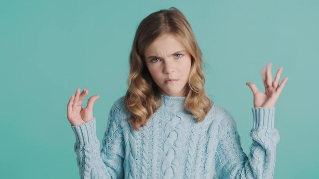 Bored blond teenage girl showing bla bla gesture has not interested conversation looking angry over blue background