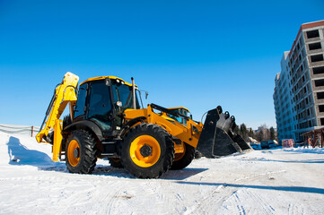 the new yellow excavator stands against the blue sky