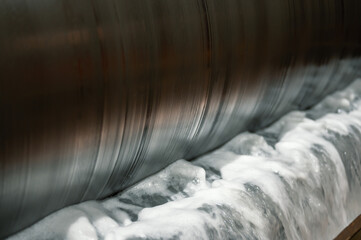 Metal drum of magnetic separator, bubbling and foaming water.