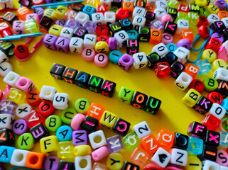Selective focus.Colorful dice with word THANK YOU on yellow background.Shot were noise and film grain.