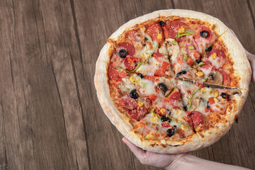 Chef or baker holding a big pizza in tomato sauce with black olives