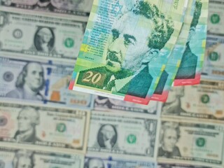 approach to israeli banknotes and background with american dollar bills
