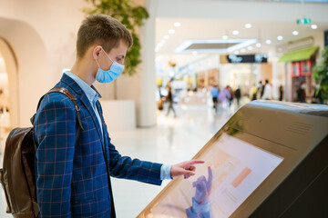 young man in a shopping mall looks at the monitor in a mask, the concept of internet search