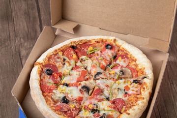 Pepperoni pizza with black olives in a cardboard takeaway box