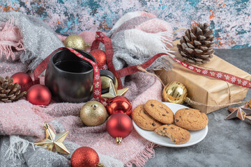 Crispy ginger cookies in a white saucer with a cup of drink and christmas