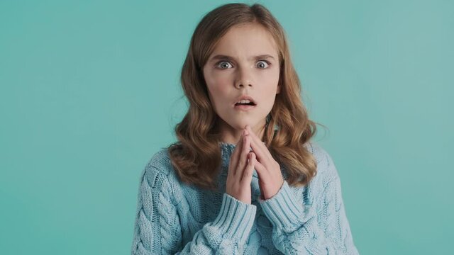 Terrified blond teenager girl looking scared posing on camera over colorful background