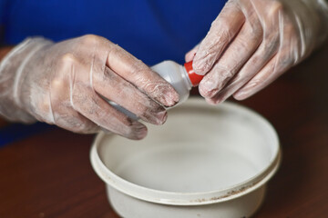 man's gloved hands unscrew bottle cap