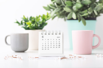 Calendar and pins with pastel mugs and plant in pots
