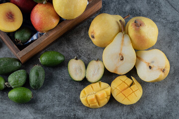 Red peaches, pears and green feijoas on the grey marble