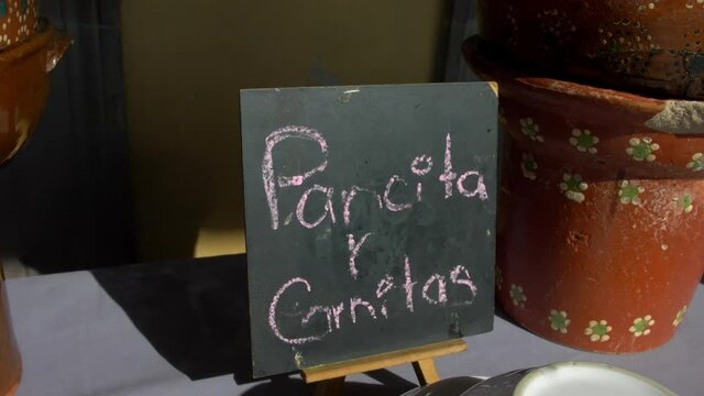 Black sign with Spanish text and clay pots on a table
