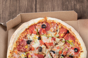 Pepperoni pizza with black olives in a cardboard takeaway box