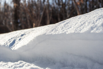 Large snowdrift on the side of a forest road for cars. High drifts after a snowfall or blizzard.