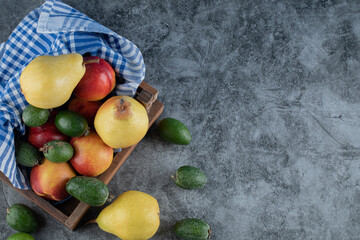 A wooden fruit tray full of pears, feijoas and peaches