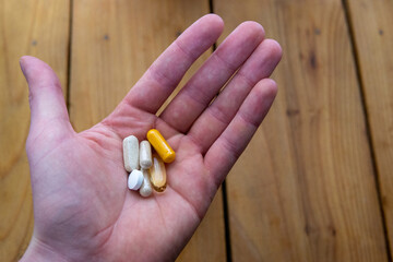 A handful of health supplements over wooden counter