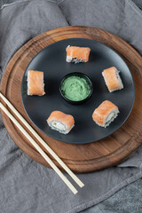 Salmon rolls in a black platter with wasabi sauce