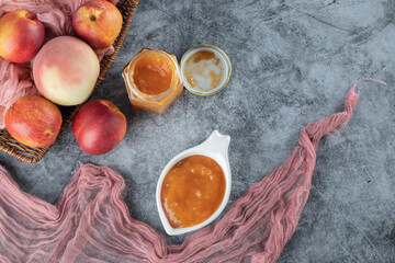 Peach and apples in a wooden basket on a piece of pink towel 