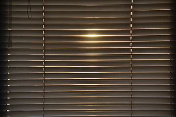 Sunlight through the closed blinds by the window