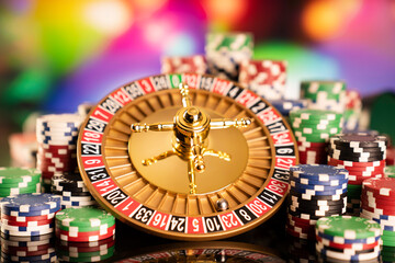 Casino theme.  Gambling games. Roulette, dice and poker chips on a colorful bokeh background.