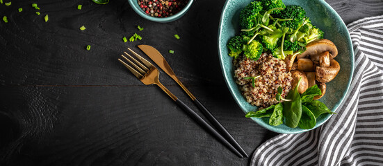 Healthy food. Fresh green salad with quinoa, spinach, broccoli, mushrooms and microgreens on dark background, top view