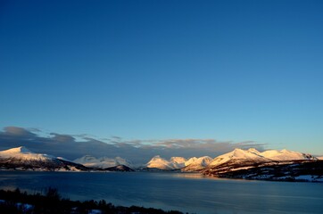 sunset over fjord and snowy mountain range in northern Norway