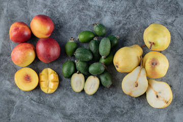 Red peaches, pears and green feijoas on the grey marble