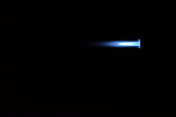 blue gas jet flame on black background