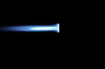 blue gas jet flame on black background