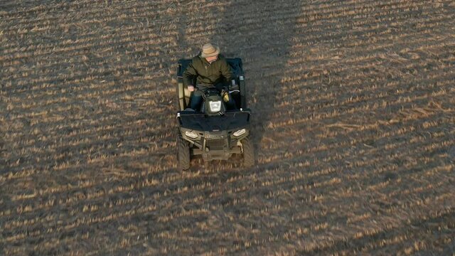 Man driving atv in farm field and taking a soli sample, aerial follow