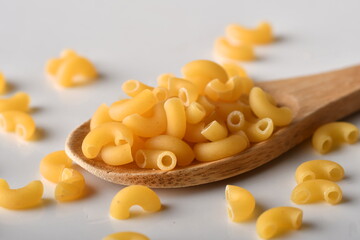 uncooked elbow macaroni on a white background.
