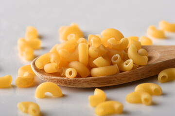 uncooked elbow macaroni on a white background.
