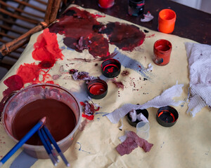 High angle view at artists palettes splattered with paint lying on the table lit by sunlight,...
