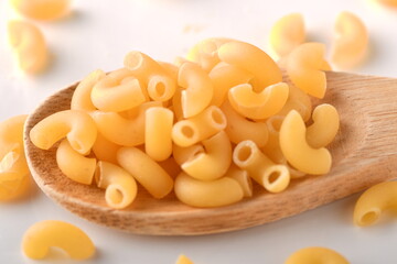 uncooked elbow macaroni on a white background.
