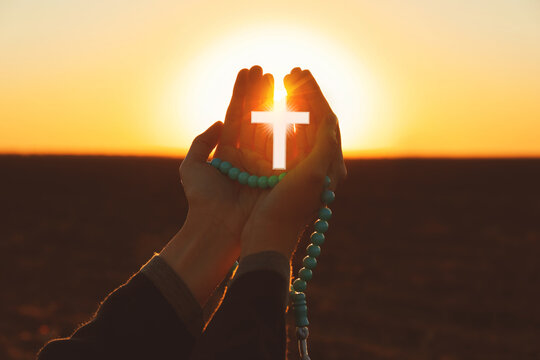 Young Muslim woman praying with beads outdoors at sunrise