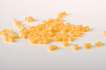 uncooked elbow macaroni on a white background.
