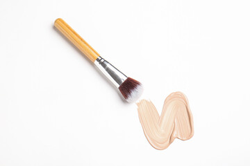 Sample of makeup foundation and brush on white background