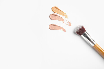 Samples of makeup foundation and brush on white background