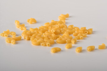 uncooked elbow macaroni on a white background.
