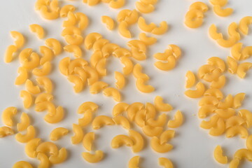uncooked elbow macaroni on a white background.
