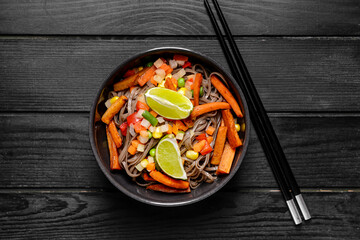 Bowl with tasty soba noodles and meat on dark wooden background
