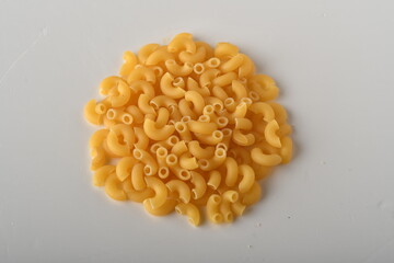 uncooked elbow macaroni on a white background.
