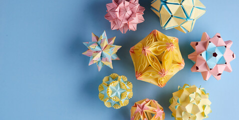 Set of multicolor handmade modular origami balls or Kusudama Isolated on blue background. Visual art, geometry, art of paper folding, paper crafts. Top view, close up, selective focus, copy space.
