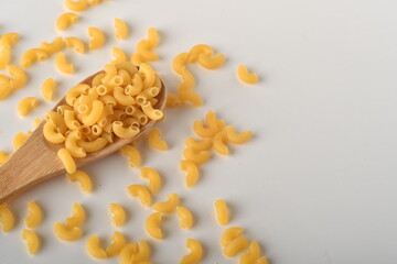 uncooked elbow macaroni on a white background.
