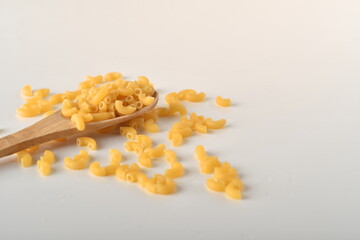 uncooked elbow macaroni on a white background.
