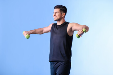 Sporty young man training with dumbbells on color background