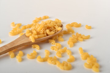 uncooked elbow macaroni on a white background.
