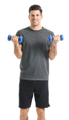 Sporty young man training with dumbbells on white background